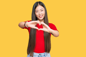 Young chinese woman wearing casual clothes smiling in love doing heart symbol shape with hands. romantic concept.