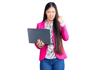 Naklejka premium Young beautiful chinese woman using laptop annoyed and frustrated shouting with anger, yelling crazy with anger and hand raised