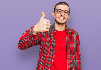 Hispanic young man wearing casual clothes doing happy thumbs up gesture with hand. approving...