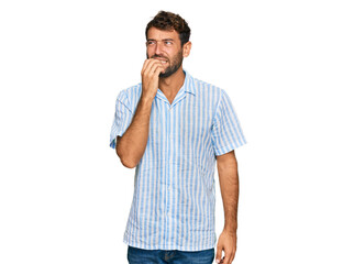 Handsome young man with beard wearing casual fresh shirt looking stressed and nervous with hands on mouth biting nails. anxiety problem.