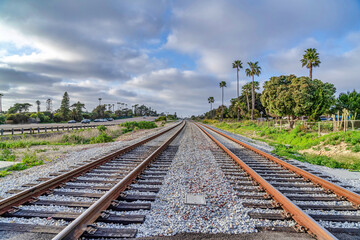 Obraz premium Railway tracks along road against overcast blue sky in San Diego California