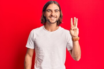 Naklejka premium Young handsome man wearing casual clothes showing and pointing up with fingers number three while smiling confident and happy.
