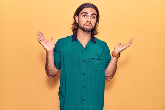 Young handsome man wearing casual clothes clueless and confused with open arms, no idea and doubtful face.