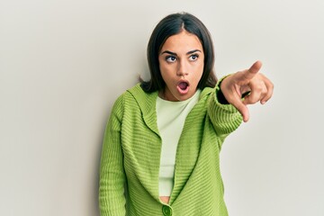 Young brunette woman wearing casual clothes pointing with finger surprised ahead, open mouth amazed expression, something on the front