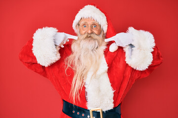 Old senior man with grey hair and long beard wearing traditional santa claus costume smiling cheerful showing and pointing with fingers teeth and mouth. dental health concept.