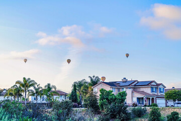 Hot air balloons and scenic sky over homes and trees in San Diego California