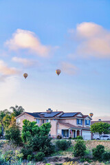 Fototapeta na wymiar House with solar panels on roof under hot air balloons in San Diego California