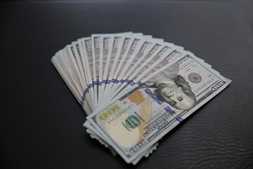 Set of 100 US dollar bills on black leather background. Many american banknotes