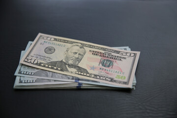 Set of 100 and 50 US dollar bills on black leather background. Many american banknotes