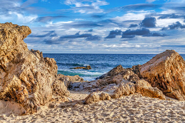 Laguna Beach California shore with rocks and sand against ocean and cloudy sky