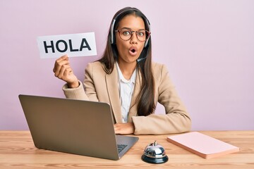 Beautiful hispanic woman wearing operator headset holding hola greenting scared and amazed with open mouth for surprise, disbelief face © Krakenimages.com