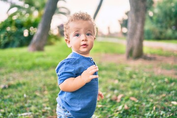 Cute and happy little boy having fun at the park on a sunny day. Beautiful blonde hair male toddler playing outdoors