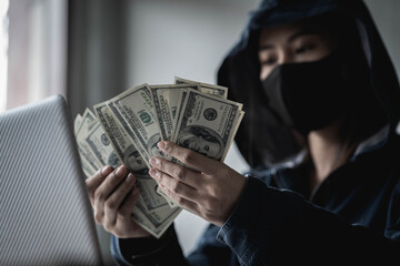 Dangerous Hooded Hacker held the money after successfully hacking.