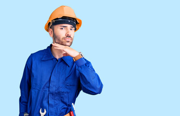 Young hispanic man wearing worker uniform cutting throat with hand as knife, threaten aggression with furious violence