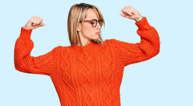 Beautiful blonde woman wearing casual clothes and glasses showing arms muscles smiling proud. fitness concept.