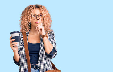 Young blonde woman with curly hair wearing leather bag and drinking a take away cup of coffee...