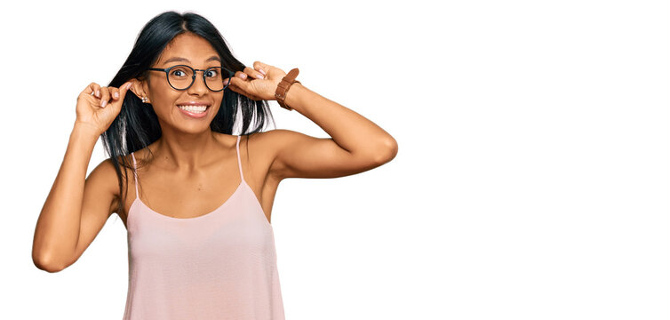 Young african american woman wearing casual clothes and glasses smiling pulling ears with fingers, funny gesture. audition problem
