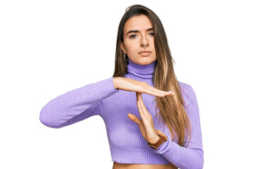 Young hispanic woman wearing casual clothes doing time out gesture with hands, frustrated and...