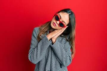 Young brunette woman wearing fashion and modern look sleeping tired dreaming and posing with hands together while smiling with closed eyes.