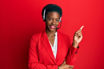 Young african american girl wearing call center agent headset smiling happy pointing with hand and finger to the side