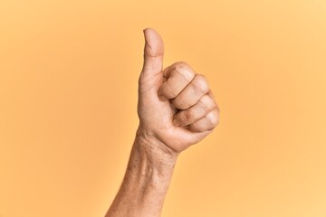 Senior caucasian hand over yellow isolated background doing successful approval gesture with thumbs up, validation and positive symbol