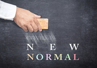 Text for New Normal and doctor hand erasing Covid-19 from a chalkboard
