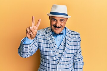 Mature middle east man with mustache wearing vintage and elegant fashion style showing and pointing up with fingers number two while smiling confident and happy.