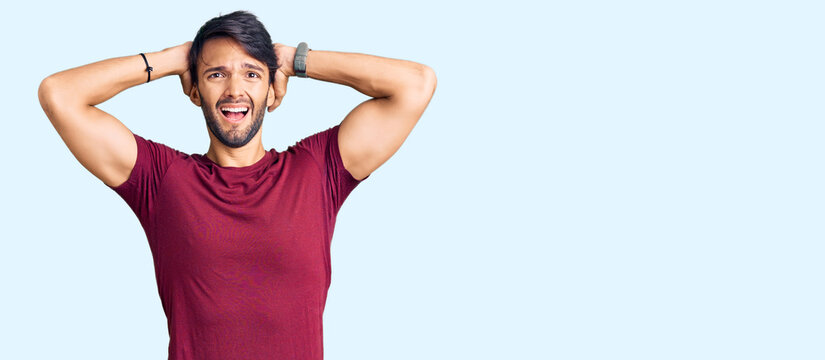 Handsome hispanic man wearing casual clothes crazy and scared with hands on head, afraid and surprised of shock with open mouth