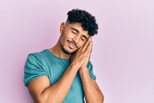 Young arab handsome man wearing casual clothes sleeping tired dreaming and posing with hands together while smiling with closed eyes.