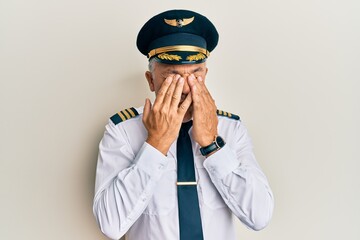 Handsome middle age mature man wearing airplane pilot uniform rubbing eyes for fatigue and...