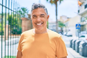 Middle age grey-haired man smiling happy walking at street of city.