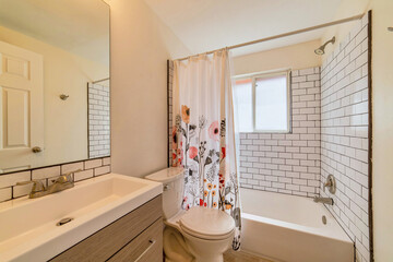 Toilet vanity and built in bathtub with floral shower curtain inside bathroom