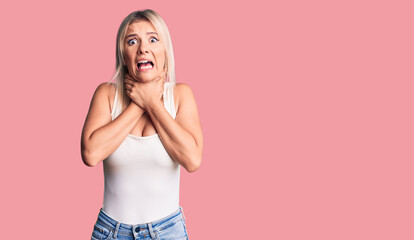Young beautiful blonde woman wearing casual sleeveless t-shirt shouting and suffocate because...