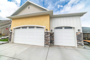 Facade of residential two car garage with gable roof and white panelled doors