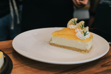 Pieces of delicious homemade lemon cheesecake with slices of lemon and mint served on a white plate. Delicious fruit dessert.food concept