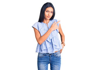 Young beautiful latin girl wearing casual clothes pointing with hand finger to the side showing advertisement, serious and calm face