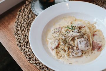 Italian pasta - Spagetti carbonara with pancetta, egg, hard parmesan cheese and cream sauce. in the white plate on woodden table .