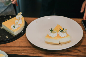 Pieces of delicious homemade lemon cheesecake with slices of lemon and mint served on a white plate. Delicious fruit dessert.food concept