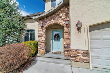 Home with arched stone exterior entryway and glass paned front door with wreath