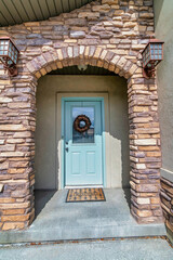Stone brick arch and glass paned white front door at the entrance of a house