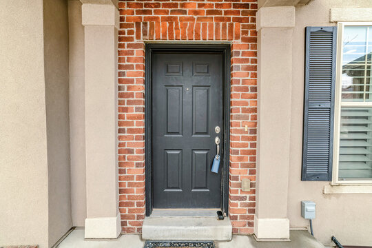 Dark gray wooden front door against red brick wall at the house entrance