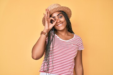 Young african american woman with braids wearing summer hat smiling happy doing ok sign with hand...