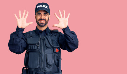 Young hispanic man wearing police uniform showing and pointing up with fingers number ten while smiling confident and happy.