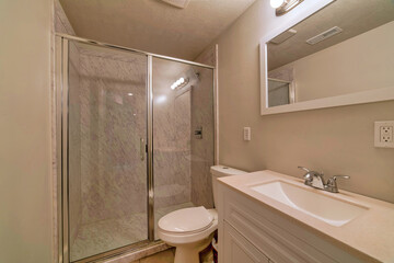 Fototapeta na wymiar Shower stall with sliding glass door beside toilet and sink on white countertop