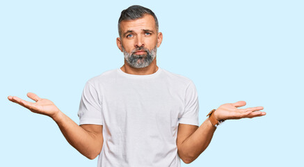 Middle age handsome man wearing casual white tshirt clueless and confused with open arms, no idea...