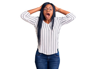 Young african american woman wearing casual clothes and glasses crazy and scared with hands on head, afraid and surprised of shock with open mouth
