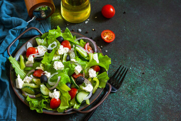 Healthy diet food. Greek salad of feta cheese, fresh cucumber, tomato, sweet pepper, lettuce, red onion and olives with olive oil. Copy space.