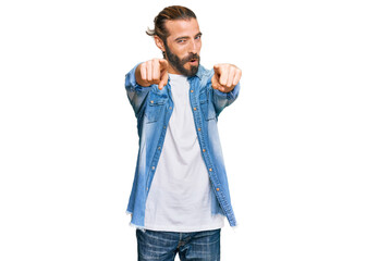 Attractive man with long hair and beard wearing casual denim jacket pointing to you and the camera with fingers, smiling positive and cheerful