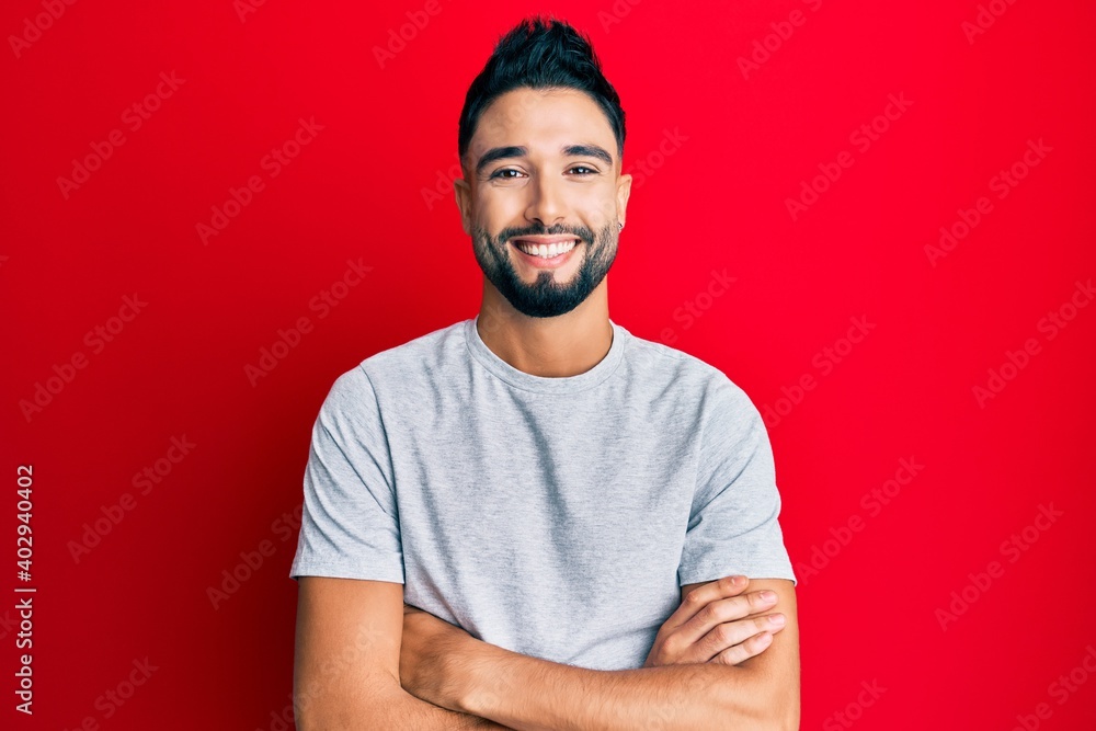 Wall mural Young man with beard wearing casual white tshirt happy face smiling with crossed arms looking at the camera. positive person.