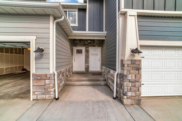 Townhouses with side by side front doors and steps between attached garages